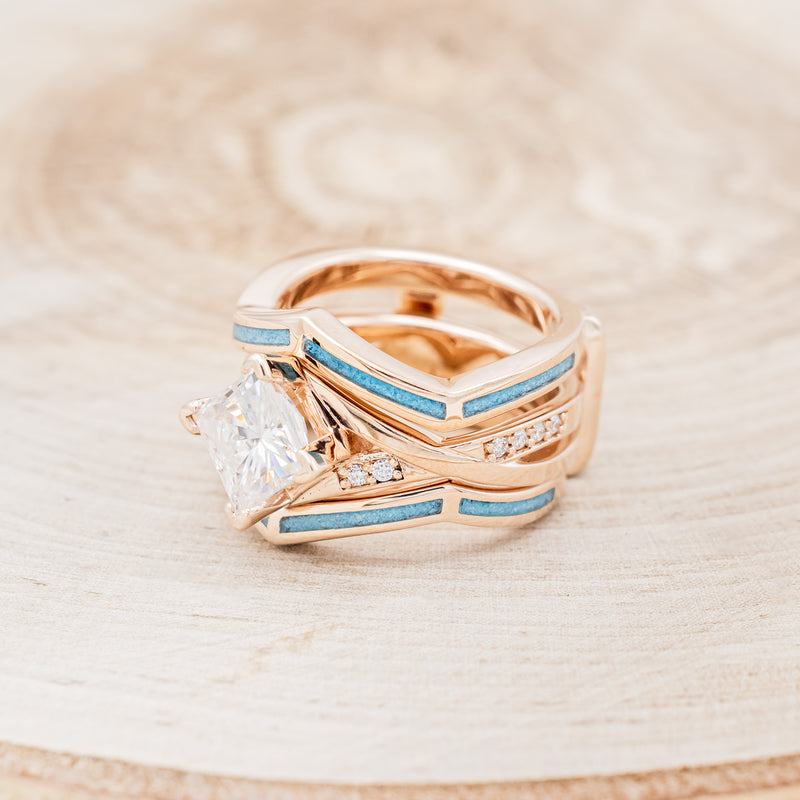 Shown here is "Lina", a moissanite women's engagement ring with diamond accents and a turquoise ring guard, facing left. Many other center stone options are available upon request.