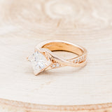 Shown here is "Lina", a moissanite women's engagement ring with diamond accents, facing left. Many other center stone options are available upon request.