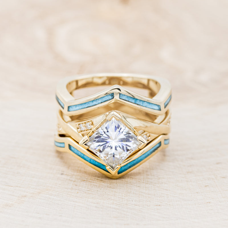 Shown here is "Lina", a moissanite women's engagement ring with diamond accents and a turquoise ring guard, front facing. Many other center stone options are available upon request.