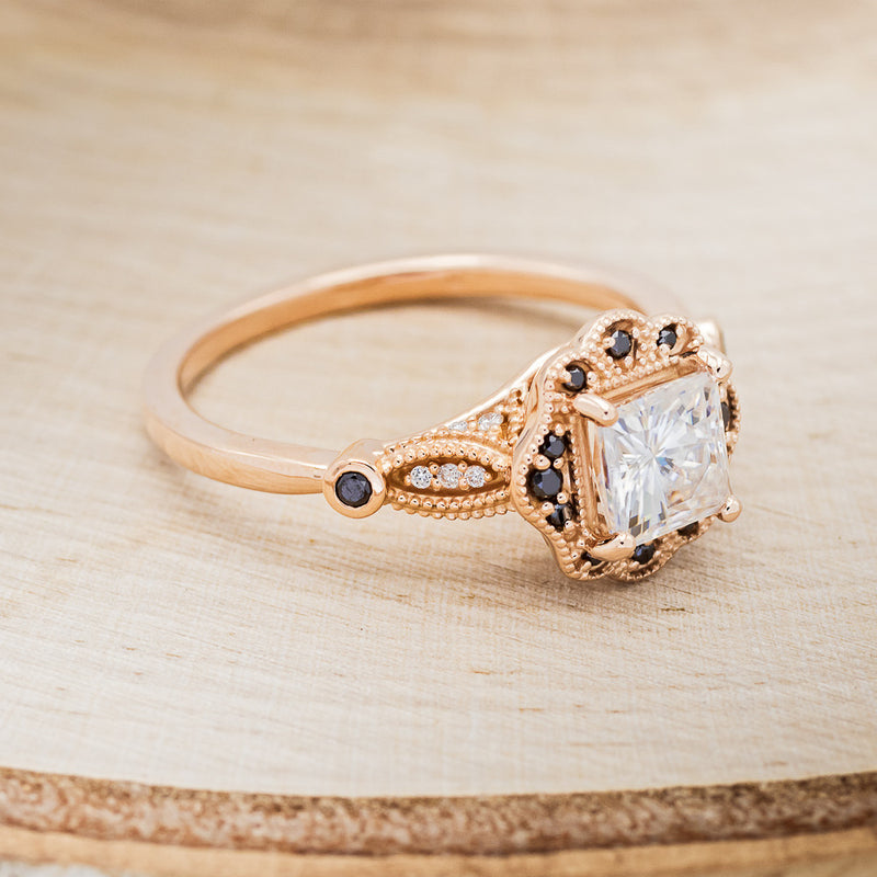 Shown here is "Eileen", a vintage-style moissanite women's engagement ring with black diamond accents, facing right. Many other center stone options are available upon request.