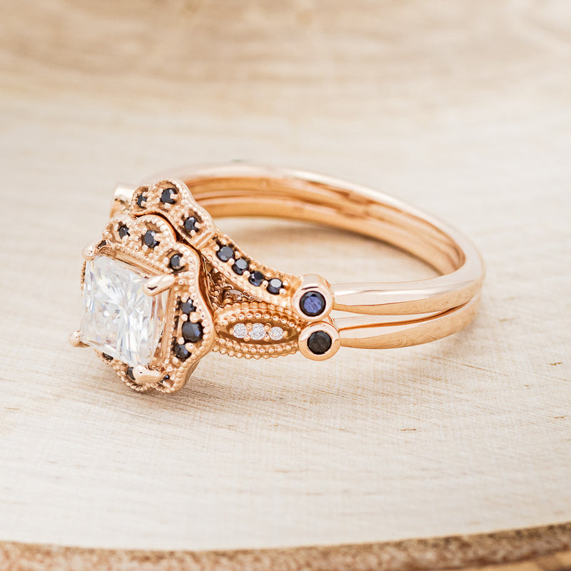 Shown here is "Eileen", a vintage-style moissanite women's engagement ring with black diamond accents and tracer, facing left. Many other center stone options are available upon request.