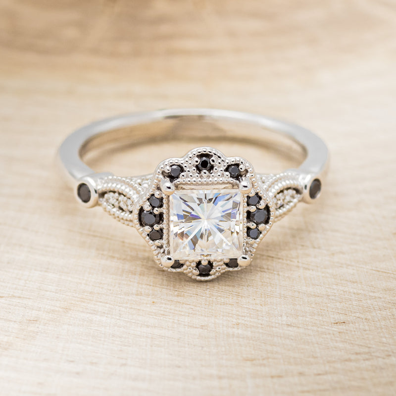 Shown here is "Eileen", a vintage-style moissanite women's engagement ring with black diamond accents, front facing. Many other center stone options are available upon request.
