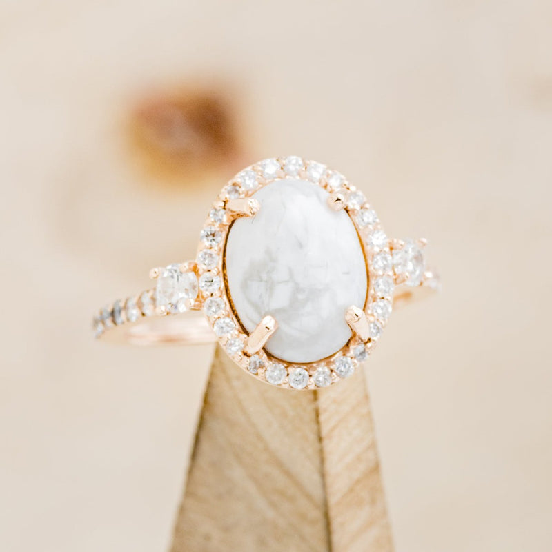 Shown here is "KB", an oval white buffalo turquoise women's engagement ring with a diamond halo and diamond accents, on stand front facing. Many other center stone options are available upon request. 