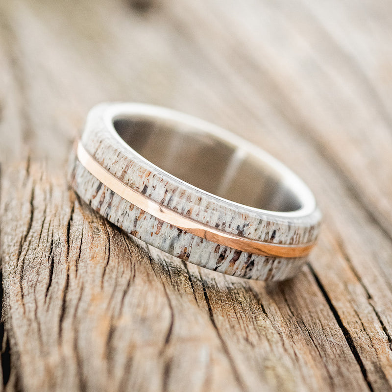 Shown here is "Golden", a handcrafted men's wedding ring featuring a naturally shed elk antler divided by a 14K rose gold inlay, tilted left. Additional inlay options are available upon request.