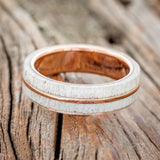 Shown here is "Golden", a handcrafted men's wedding ring featuring a naturally shed elk antler divided by a 14K rose gold inlay, laying flat. Additional inlay options are available upon request.
