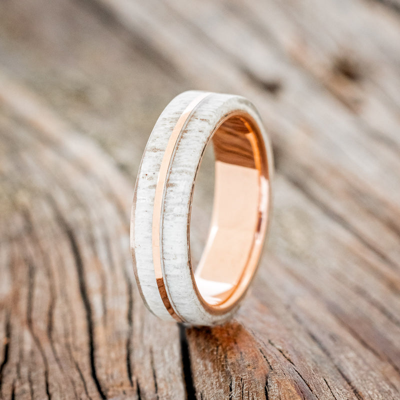 Shown here is "Golden", a handcrafted men's wedding ring featuring a naturally shed elk antler divided by a 14K rose gold inlay, upright facing left. Additional inlay options are available upon request.
