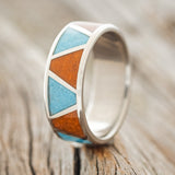 Shown here is "Powell", a custom, handcrafted men's wedding ring featuring a terracotta & turquoise inlay, upright facing left. Additional inlay options are available upon request.