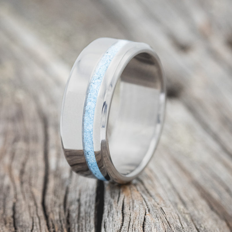 Shown here is "Vertigo", a handcrafted men's wedding ring shown featuring a turquoise inlay, upright facing left. 