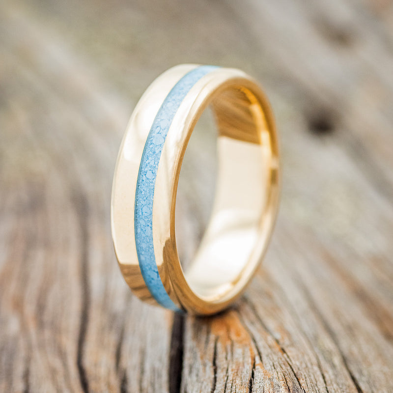 Shown here is "Vertigo", a custom, handcrafted narrow men's wedding ring featuring a turquoise inlay, upright facing left. Additional inlay options are available upon request.