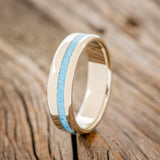 Shown here is "Vertigo", a custom, handcrafted narrow men's wedding ring featuring a turquoise inlay, upright facing left. Additional inlay options are available upon request.