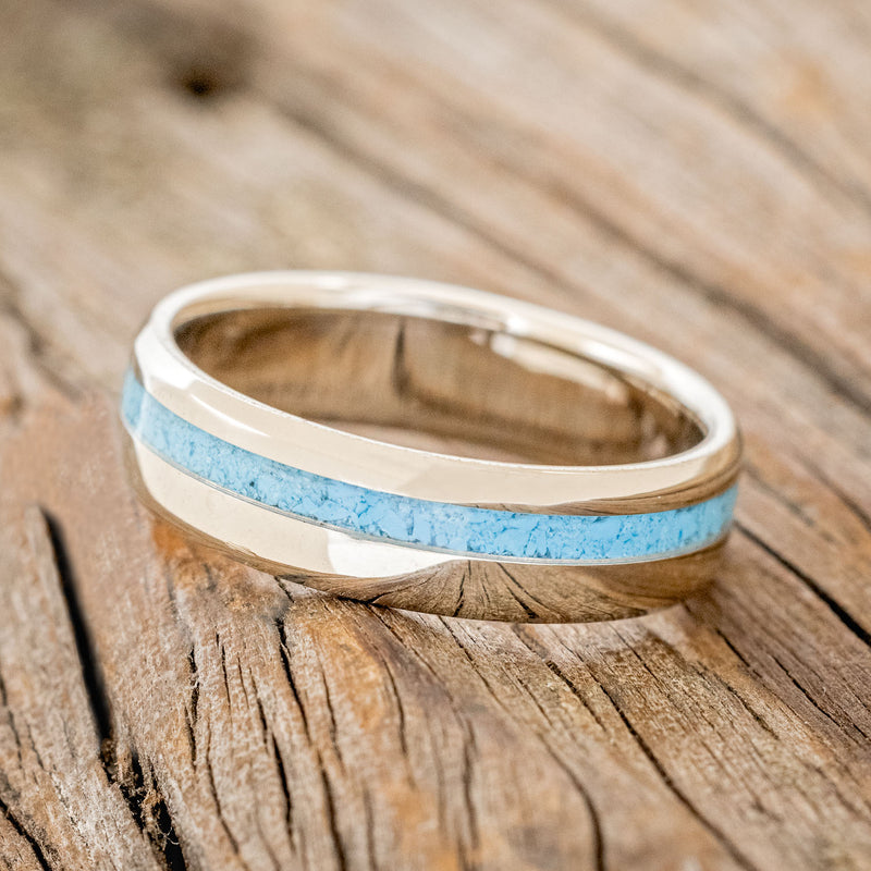 Shown here is "Vertigo", a custom, handcrafted narrow men's wedding ring featuring a turquoise inlay, tilted left. Additional inlay options are available upon request.