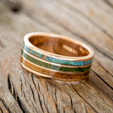 Shown here is "Rio", a custom, handcrafted men's wedding ring featuring 3 channels with patina copper, moss and whiskey barrel oak inlays on a 14K gold band, tilted left. Additional inlay options are available upon request.