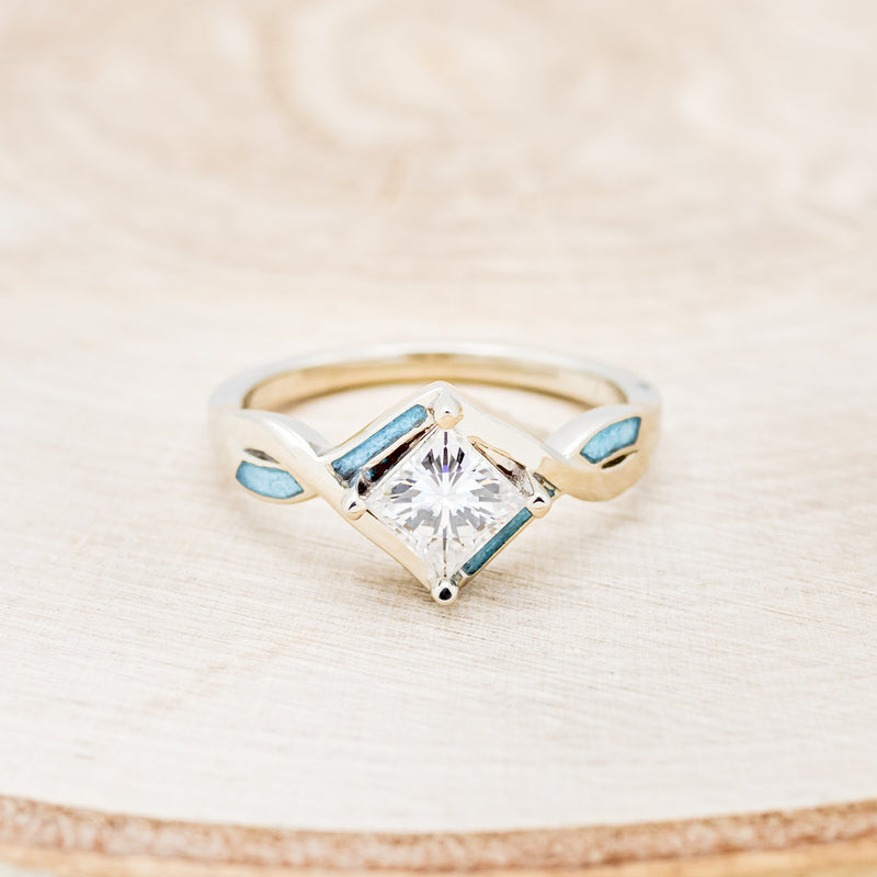 Shown here is "Adamas", a prong-style moissanite women's engagement ring with turquoise inlays, front facing. Many other center stone options are available upon request.