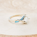 Shown here is "Adamas", a prong-style moissanite women's engagement ring with turquoise inlays, facing right. Many other center stone options are available upon request.