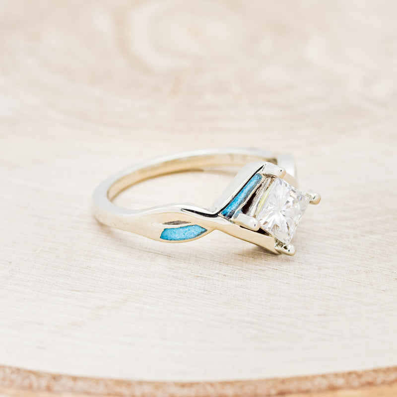 Shown here is "Adamas", a prong-style moissanite women's engagement ring with turquoise inlays, facing right. Many other center stone options are available upon request.