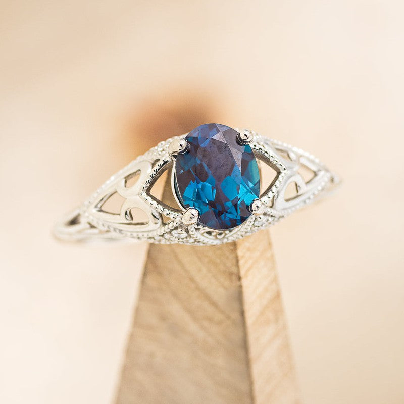 Shown here is"Relica", a vintage-style lab-created Alexandrite women's engagement ring with diamond accents, on stand facing slightly right. Many other center stone options available upon request.