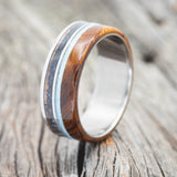 Shown here is "Element", a custom, handcrafted men's wedding ring featuring ironwood, patina copper, and a turquoise inlay, upright facing left. Additional inlay options are available upon request.