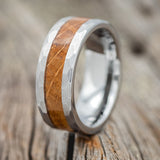 Shown here is a custom, handcrafted men's wedding ring featuring a whiskey barrel inlay with faceted edges Tungsten band, upright facing left. Additional inlay options are available upon request.
