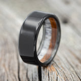 Shown here is a handcrafted men's wedding ring featuring a handcrafted ironwood & elk antler lined wedding band set on fire-treated black zirconium, upright facing left. Additional inlay options are available upon request.