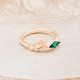 Shown here is "Sparrow", a lab-created emerald women's engagement ring with a sparrow embellishment, facing right. Many other center stone options are available upon request.