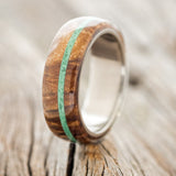 Shown here is "Remmy", a custom, handcrafted men's wedding ring featuring a redwood overlay and an offset malachite inlay, shown here on a titanium band, uptight facing left. Additional inlay options are available upon request.