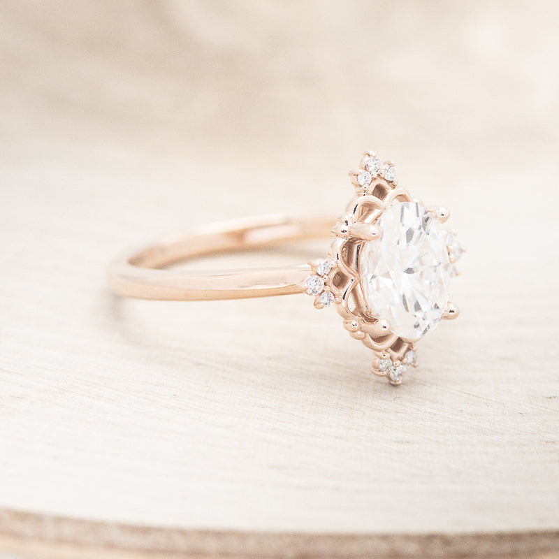 Shown here is "Treva", an oval moissanite women's engagement ring set with diamond accents, facing right. Many other center stone options are available upon request.