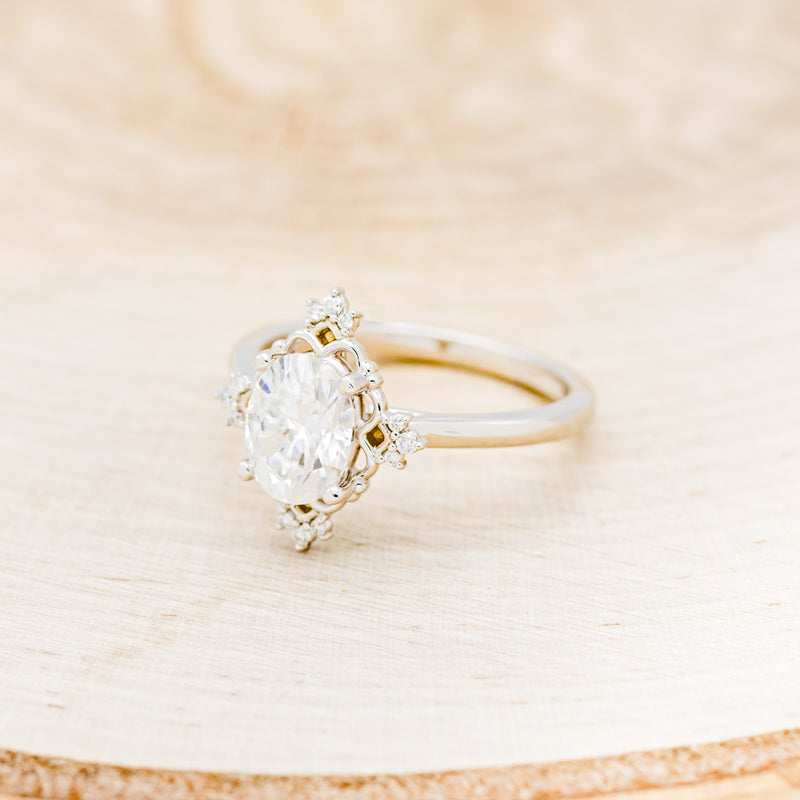 Shown here is "Treva", an oval moissanite women's engagement ring set with diamond accents, facing left. Many other center stone options are available upon request.