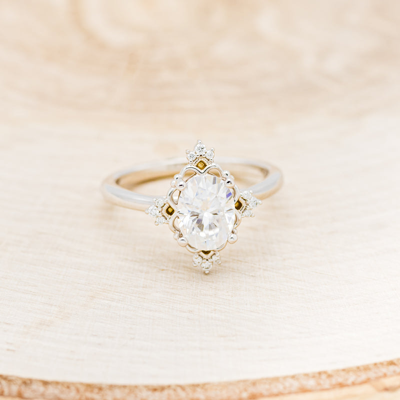 Shown here is "Treva", an oval moissanite women's engagement ring set with diamond accents, front facing. Many other center stone options are available upon request.