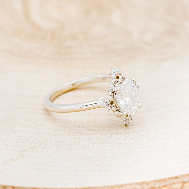 Shown here is "Treva", an oval moissanite women's engagement ring set with diamond accents, facing right. Many other center stone options are available upon request.