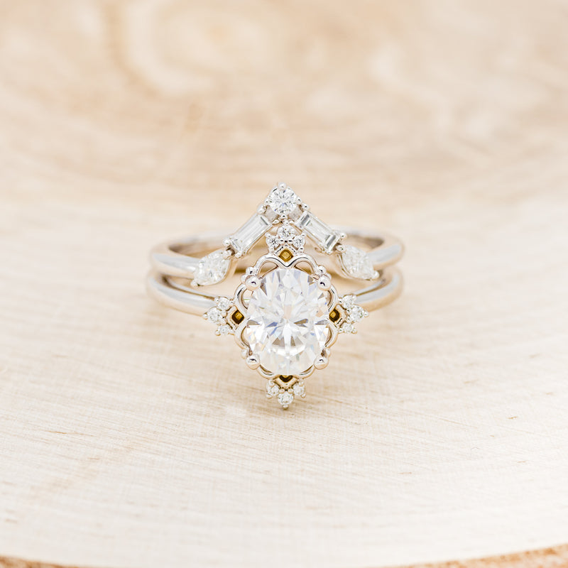 Shown here is "Treva", an oval moissanite women's engagement ring set with diamond accents and a "Melody" tracer, front facing. Many other center stone options are available upon request.
