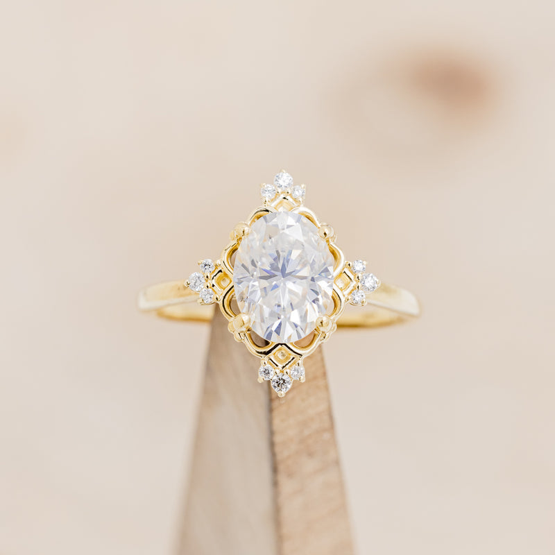 Shown here is "Treva", an oval moissanite women's engagement ring set with diamond accents, on stand front facing. Many other center stone options are available upon request.