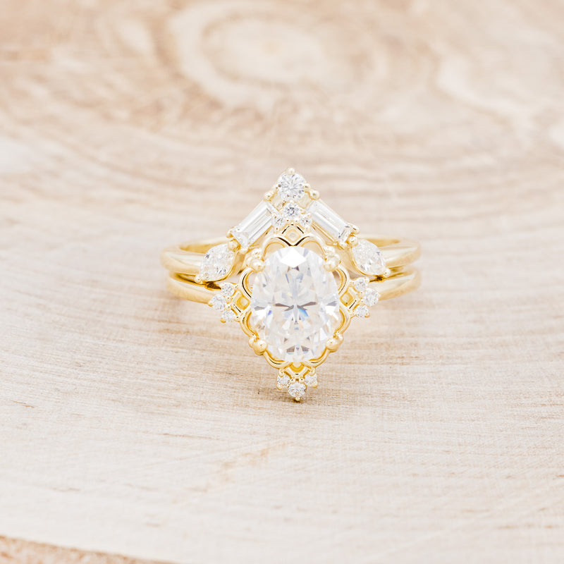 Shown here is "Treva", an oval moissanite women's engagement ring set with diamond accents and a "Melody" tracer, front facing. Many other center stone options are available upon request.