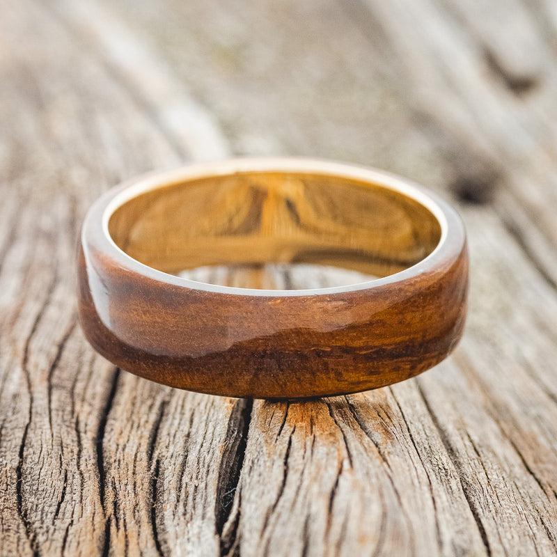 Shown here is "Haven", a custom, handcrafted men's wedding ring featuring an ironwood overlay, laying flat. Additional inlay options are available upon request.