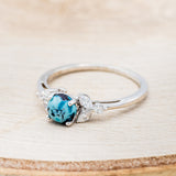 Shown here is "Blossom", a turquoise women's engagement ring with leaf-shaped diamond accents, facing left. Many other center stone options are available upon request.