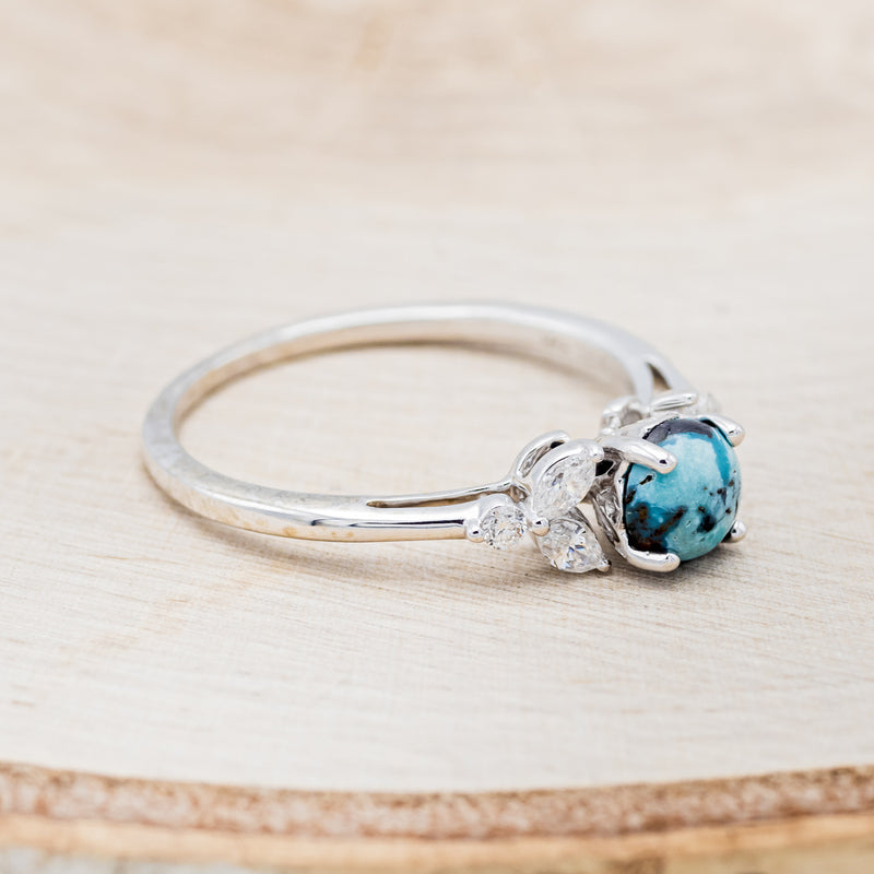 Shown here is "Blossom", a turquoise women's engagement ring with leaf-shaped diamond accents, facing right. Many other center stone options are available upon request.