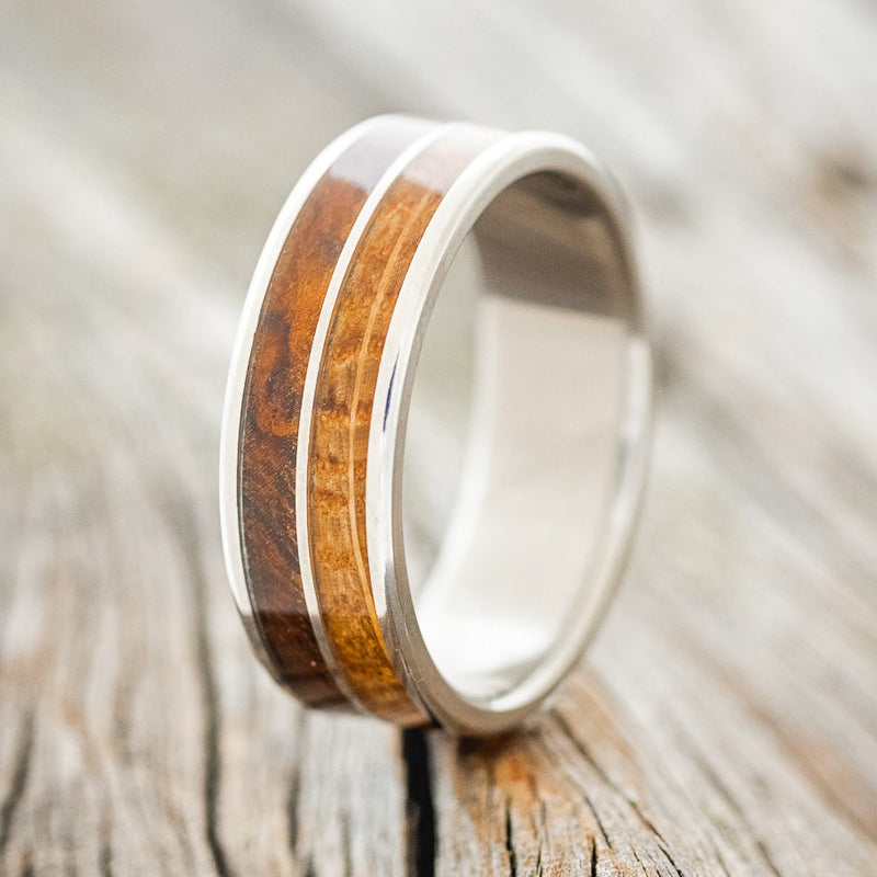Shown here is "Dyad", a custom, handcrafted men's wedding ring featuring 2 channels with whiskey barrel oak and redwood inlays, upright facing left. Additional inlay options are available upon request.
