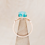 Shown here is "Lucy in the Sky", a halo-style hexagon turquoise women's engagement ring with diamond accents and turquoise inlays, side view on stand. Many other center stone options are available upon request.