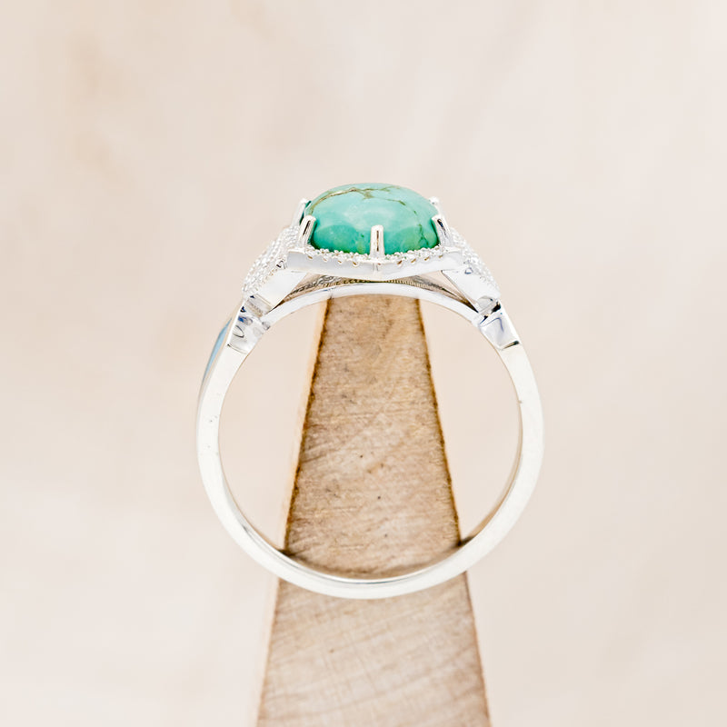 Shown here is "Lucy in the Sky", a halo-style hexagon turquoise women's engagement ring with diamond accents and turquoise inlays, side view on stand. Many other center stone options are available upon request.