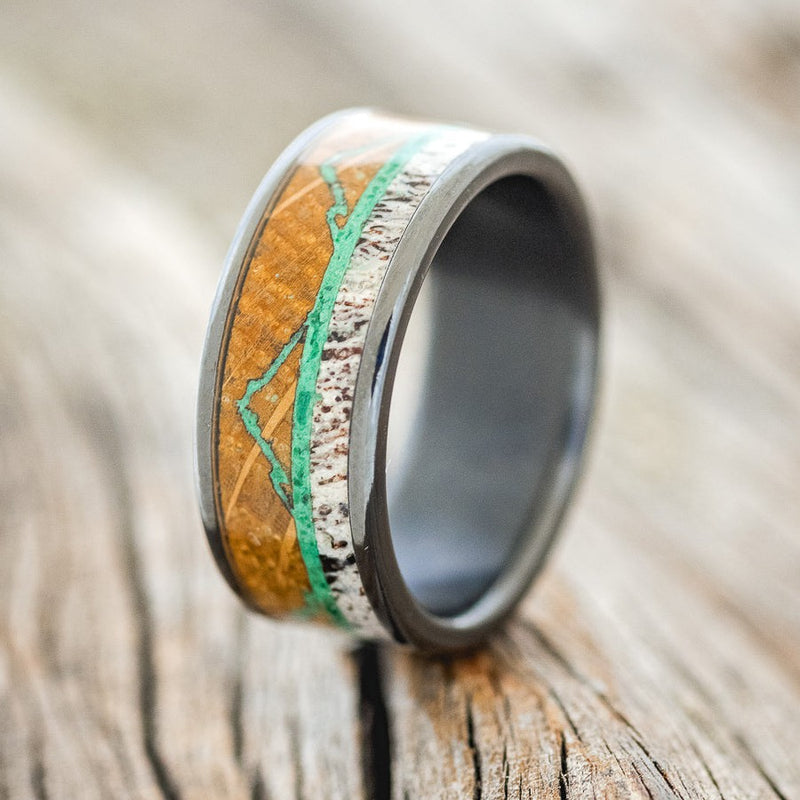 Shown here is "The Expedition", a custom, handcrafted men's wedding ring featuring a mountain engraving with whiskey barrel oak, antler and malachite inlays, upright facing left. Additional inlay options are available upon request.