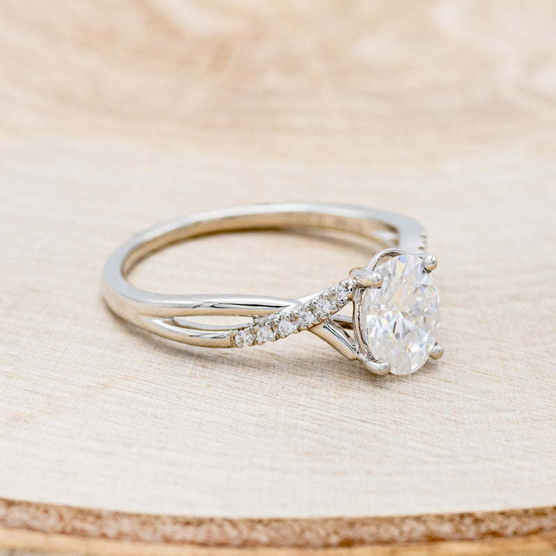 Shown here is "Roslyn", an oval moissanite women's engagement ring with diamond accents, facing right. Many other center stone options are available upon request.