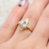 Shown here, Treva, an oval moissanite women's engagement ring set with diamond accents and a tracer, on hand. Many other center stone options are available upon request. 