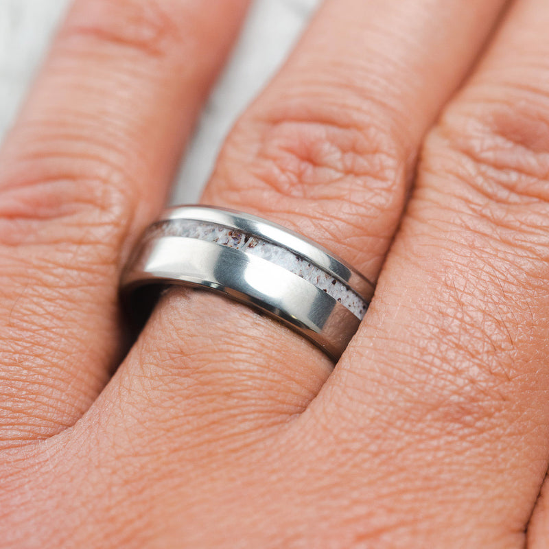 Shown here, Vertigo, a handcrafted men's wedding ring featuring an antler inlay, on hand. 