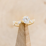 "FLORA" - ROUND CUT MOISSANITE ENGAGEMENT RING WITH LEAF-SHAPED DIAMOND ACCENTS