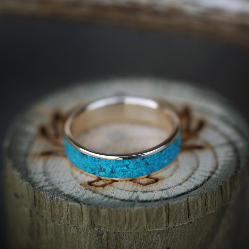 Shown here is "Rainier", a custom, handcrafted men's wedding ring featuring a crushed turquoise inlay, laying flat. Additional inlay options are available upon request.